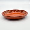 Terracotta plate with decorative patterns on a white background