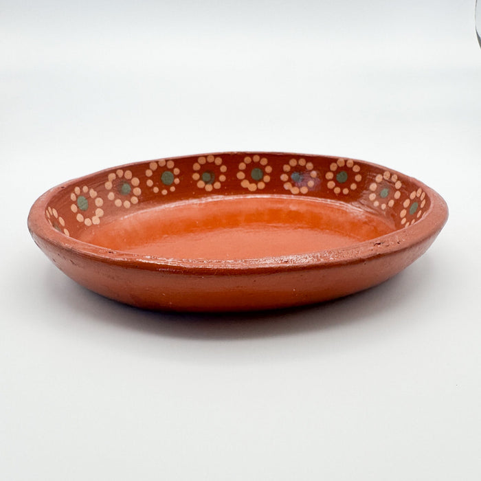 Terracotta plate with decorative patterns on a white background
