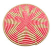 Round woven mat with pink and beige spiral pattern on a white background