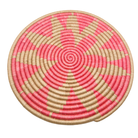 Round woven mat with pink and beige spiral pattern on a white background